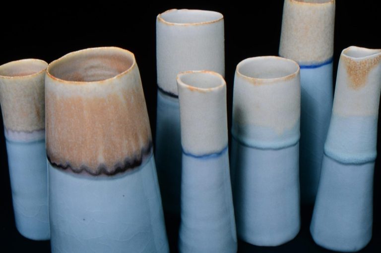 Close-up images of conical ceramic vessels that resemble mountains with bone ash and blue glazes.